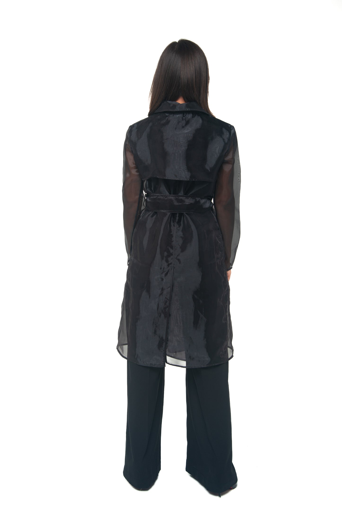 Person wearing a black sheer  long trenchcoat on a white background