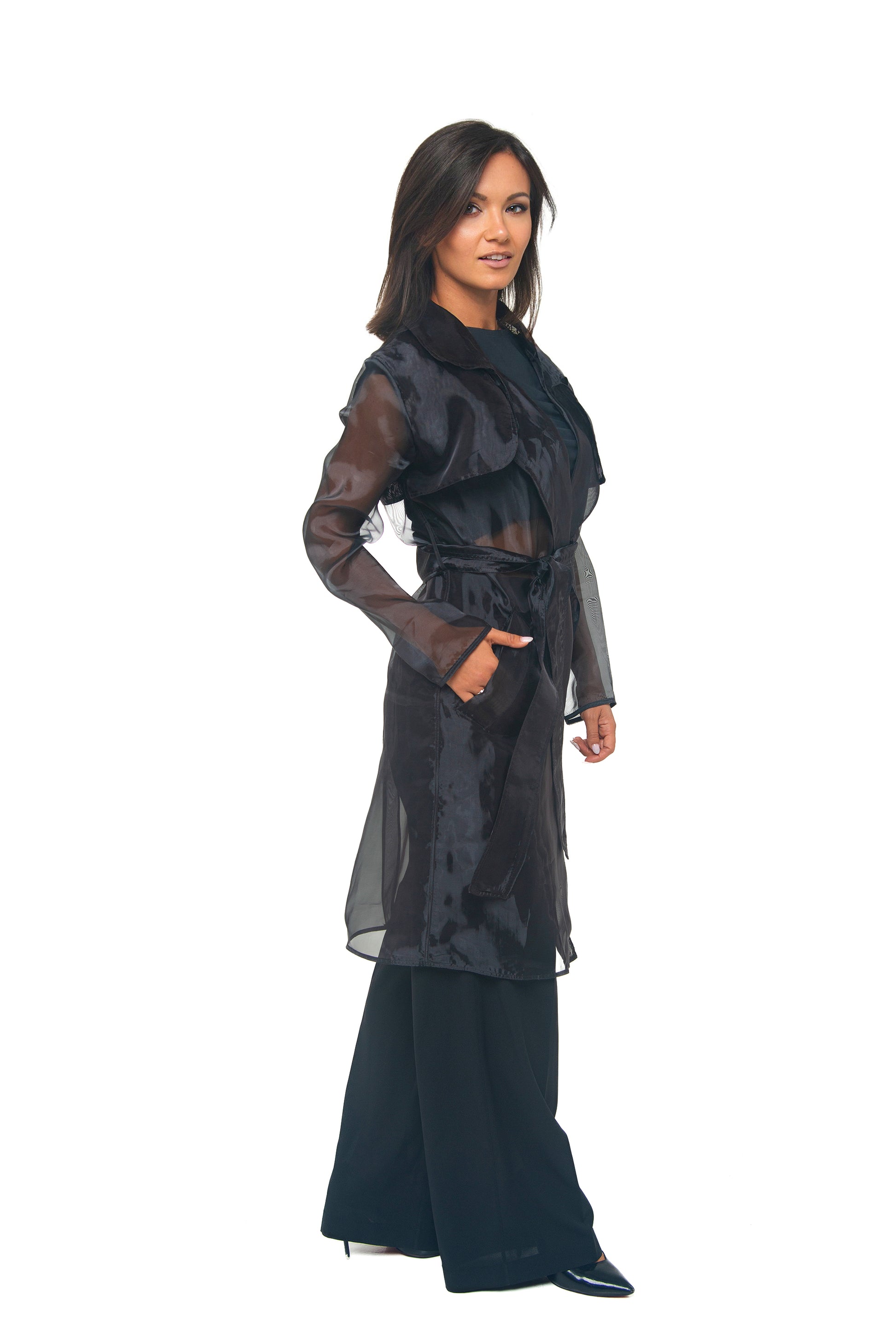Woman wearing a black outfit with sheer sleeves on a white background